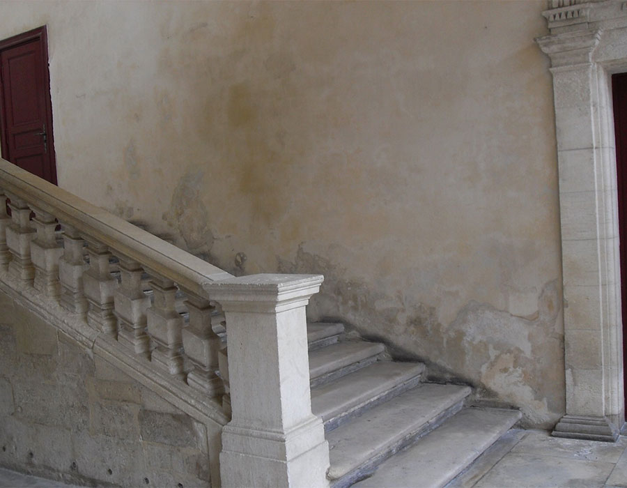 Remontées capillaire dans un mur le long d'un escalier dans un ancien bâtiment en pierre