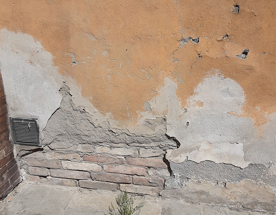 Remontées capillaires dans un mur en briques faisant tomber l'enduit