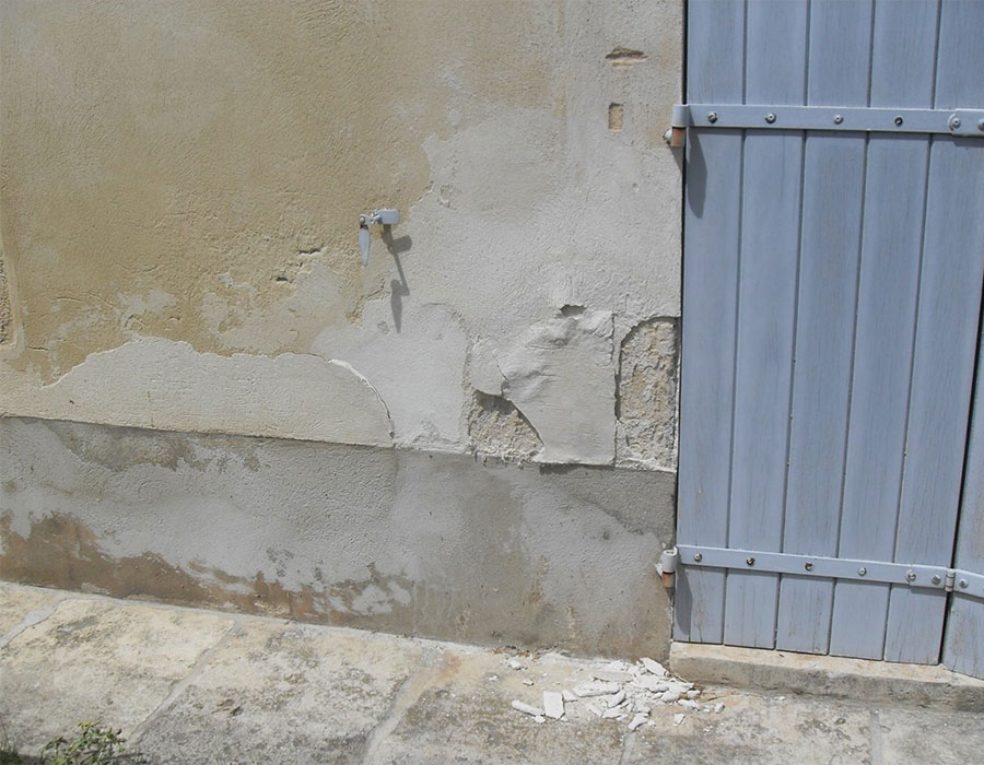 Remontées humides dans une façade faisant tomber le revêtement